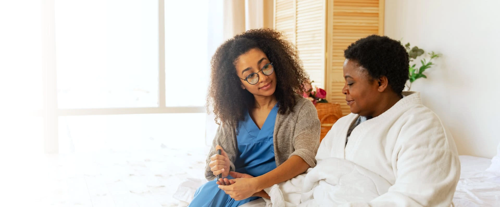 caregiver checking blood sugar level of elderly woman